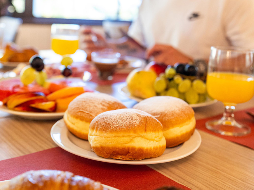 Lavagna con messaggio caloroso per una colazione deliziosa, accanto a una pianta fresca.